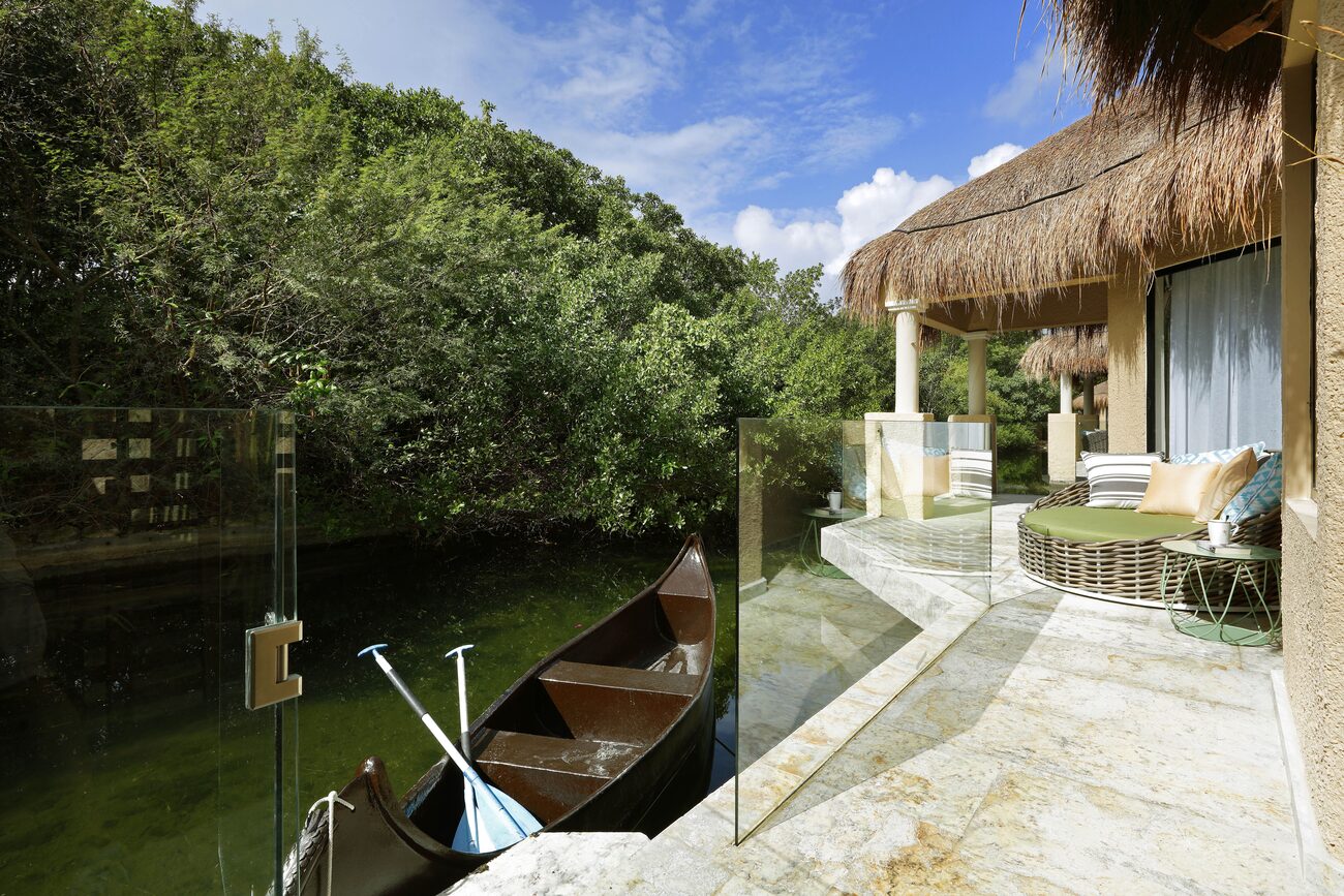 Romance Bungalows next to a calm lagoon accompanied by a hammock and canoe.