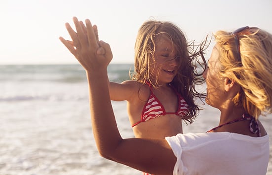 Mom giving daughter high five at the beach